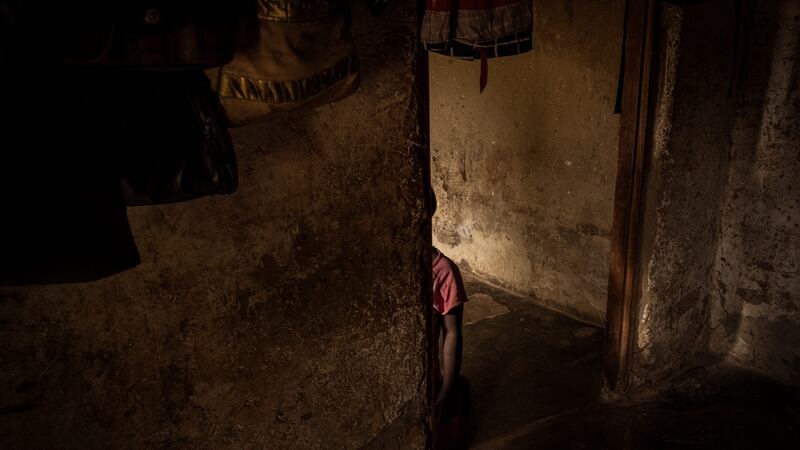 Salma Kobusinge kneels alone in her Entebbe home in Uganda. Her mother, Nono Zubeda, has said she wishes the nine-year-old was dead. Photograph: Christopher Hopkins