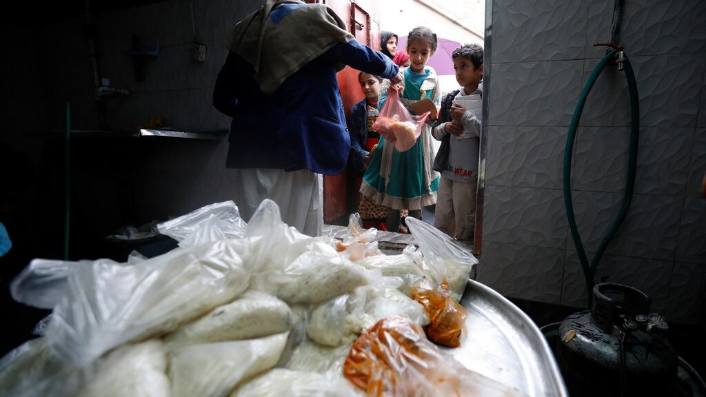 A volunteer provides free food rations to Yemeni children at a charity group in Sana’a on Sunday. Photograph: EPA