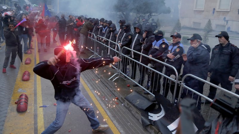 An Albanian opposition supporter throws a firework during an anti-government protest in Tirana. Photograph: Malton Dibra/EPA