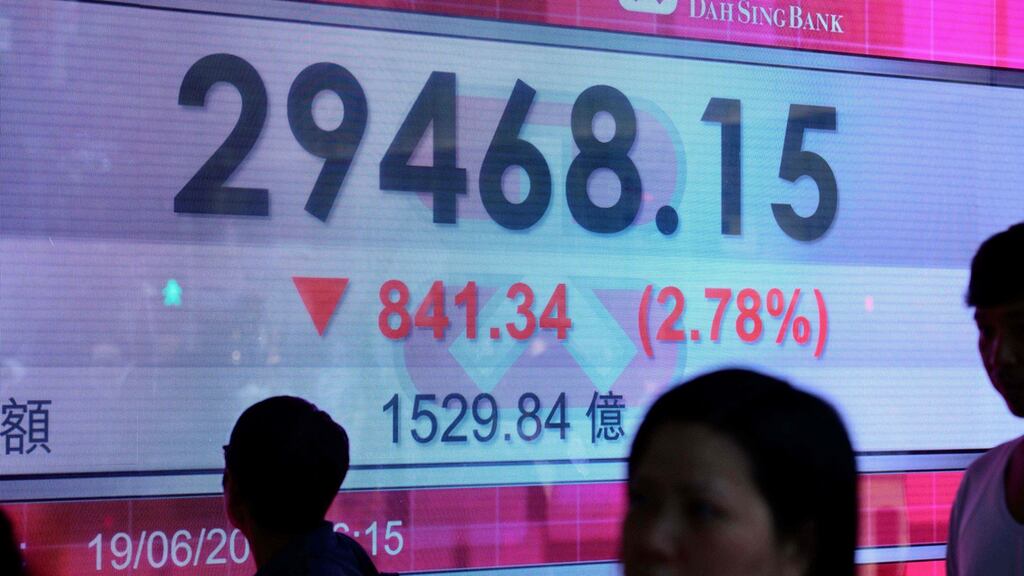 Pedestrians walk past a stocks display board after the Hang Seng Index closed at 29468.15, a loss of 2.78 pe rcent, in Hong Kong on fears of a trade war between China and the US.