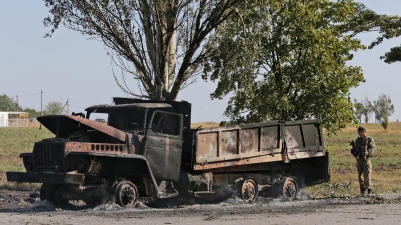 An Ukrainan soldier stands guard at a still smouldering burnt out military truck on a road in the eastern Ukrainian city of Mariupol today. Photograph: EPA