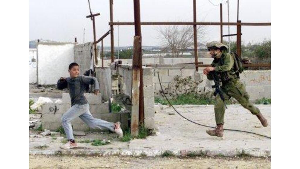 An Israeli soldier chases a Palestinian boy during clashes at a demonstration against the security barrier in the West Bank city of Qalqiliya yesterday.