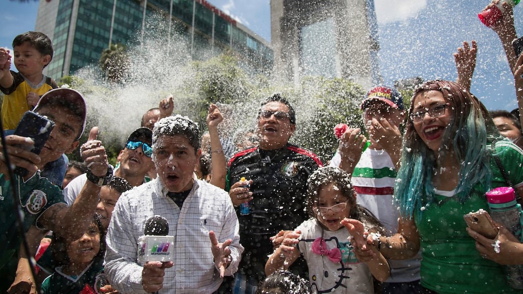 A reporter and fans are covered in foam during the celebration of Mexico’s 2018 World Cup win over Germany at the Angel of Independence in Mexico City. Photo: Anthony Vazquez/AP Photo