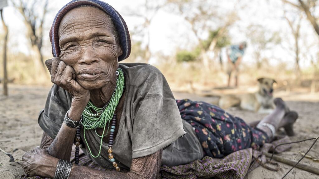 A  woman from the San tribe lying on the sandy floor of her village in a remote part of the Kalahari desert. Photograph: Jorge Fernandez/LightRocket via Getty Images