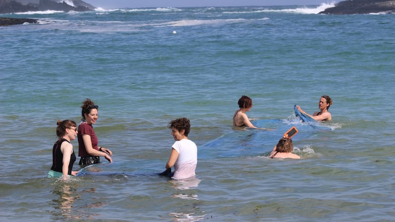Artists washing sea cyanotype from the Tombolo 19 residency and exhibition at Brow Head. Photograph Fellipe Lopes