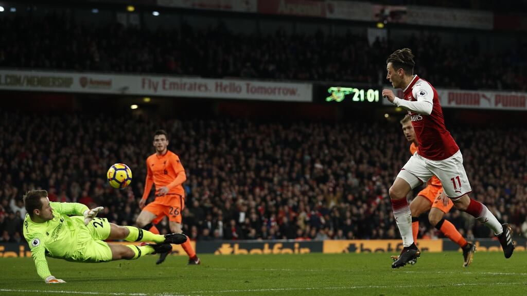Arsenal midfielder Mesut Özil chips the ball over Liverpool goalkeeper Simon Mignolet during the  Premier League game at the Emirates Stadium. Photograph:    Adrian Dennis/AFP/Getty Images