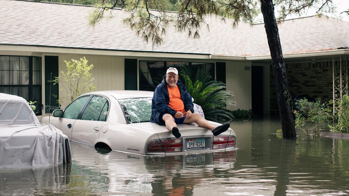 A man sits on a car as flood waters cover the Meyerland neighbourhood of Houston, Texas, US. Photograph: Alyssa Schukar/The New York Times