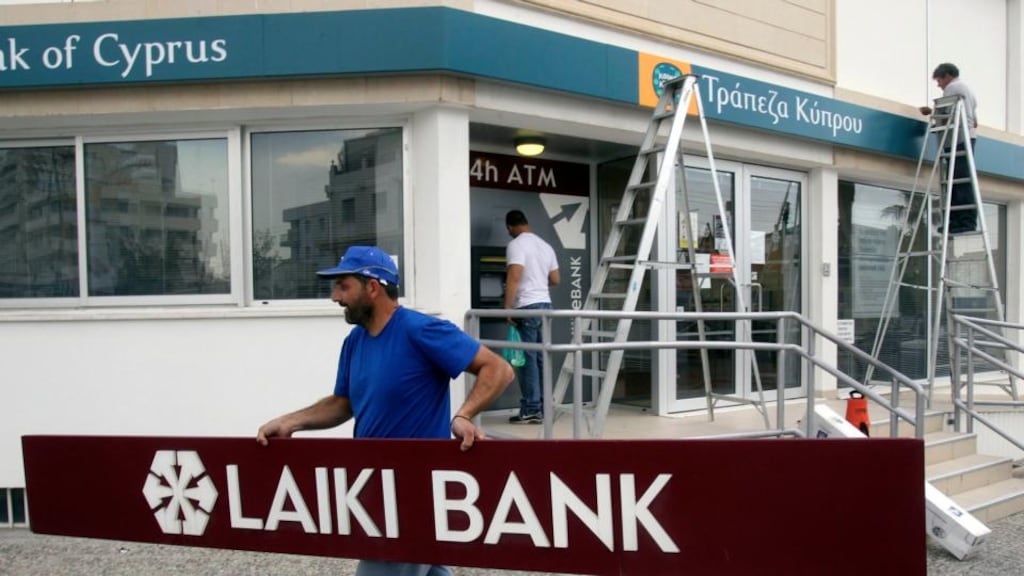 Workers remove signs from a branch of Laiki Bank in Nicosia. Photograph: Andreas Manolis/Reuters