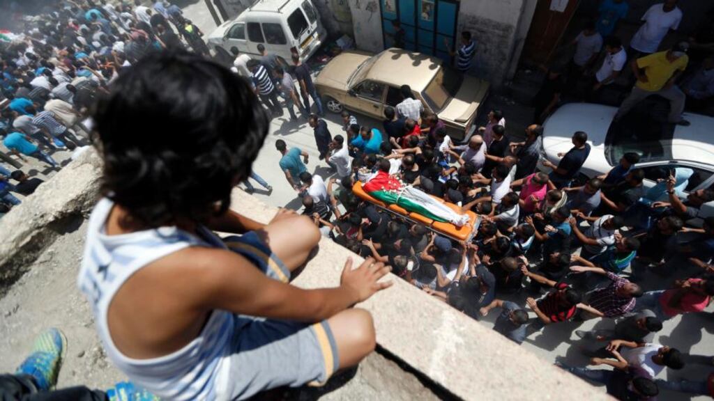 A Palestinian boy watches the funerals of Robin Zayed, Younis Jahjouh and Jihad Aslan at Qalandiya Refugee Camp near the West Bank city of Ramallah yesterday. Photograph: Mohamad Torokman/Reuters