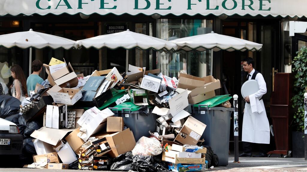 A waiter stands near a pile of rubbish bags in front of the Cafe de Flore in Paris on Wednesday, as a strike by garbage collectors continued. Photograph: Charles Platiau/Reuters
