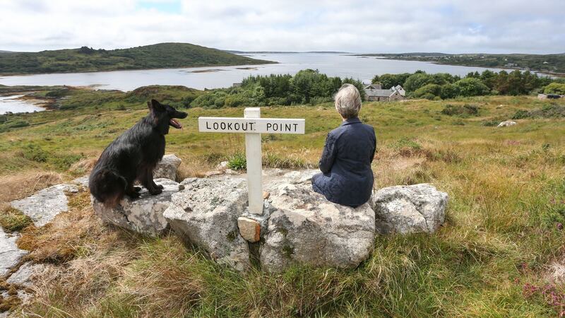 Ann Henning Jocelyn and her German Shepherd dog Pushkin at a lookout point overlooking her home in Connemara, Co Galway, with Cashel Bay and the townland of Doonreagan in the backround. Photograph: Joe O’Shaughnessy.