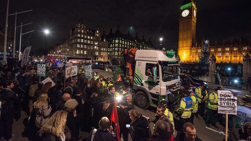 Police surround a truck after a demonstrator stopped it, and climbed underneath, during a protest outside the Houses of Parliament in central London against the British government’s proposed involvement in air strikes against the Islamic State group in Syria. Photograph: Chris Ratcliffe/AFP/Getty Images