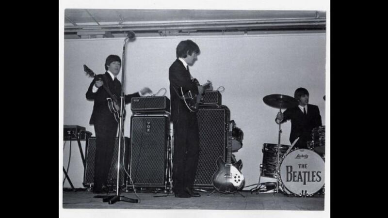 The Beatles play live in the King’s Hall in south Belfast in November 1964. Left to right are Paul McCartney, George Harrison and Ringo Starr, with John Lennon out of shot. The shot shows classic 1960s instruments awaiting play including a Rickenbacker electric guitar and a Vox Continental electric organ at left. File photograph: Nick Newbery/PRONI