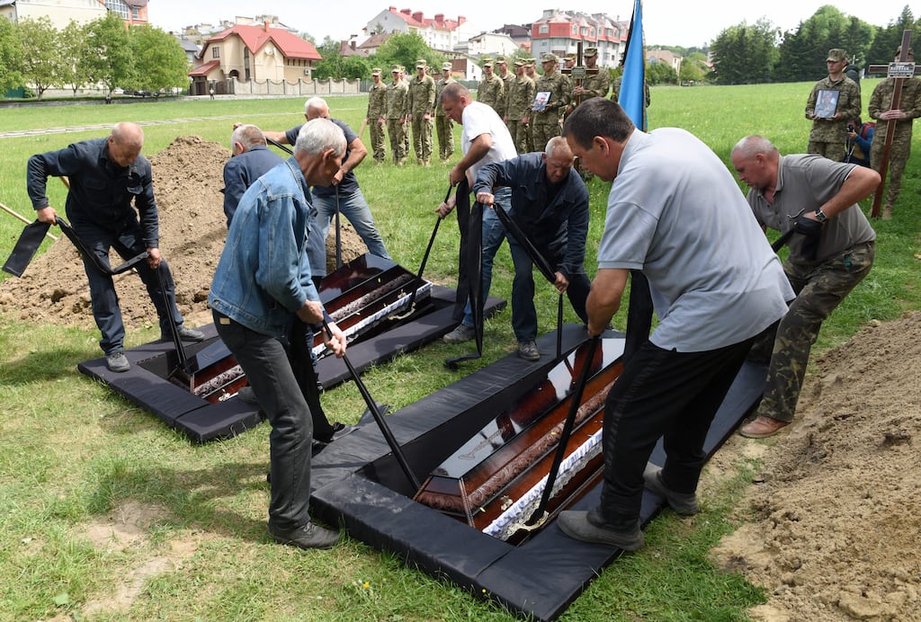 Employees put down the coffins of Andriy Vertiev and Serhiy Evtushenko, Ukrainian servicemen, killed during the Russian invasion of Ukraine, during funeral at Lychakiv cemetery in the western Ukrainian city of Lviv. Photograph: Yuriy Dyachyshyn /AFP