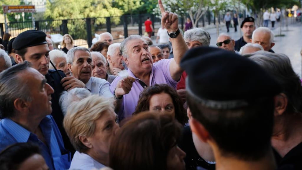 Pensioners argue with security guards at the entrance to a National Bank of Greece bank branch as they attempt to get access inside to collect their pensions in Athens, Greece. Photo: Simon Bloomberg