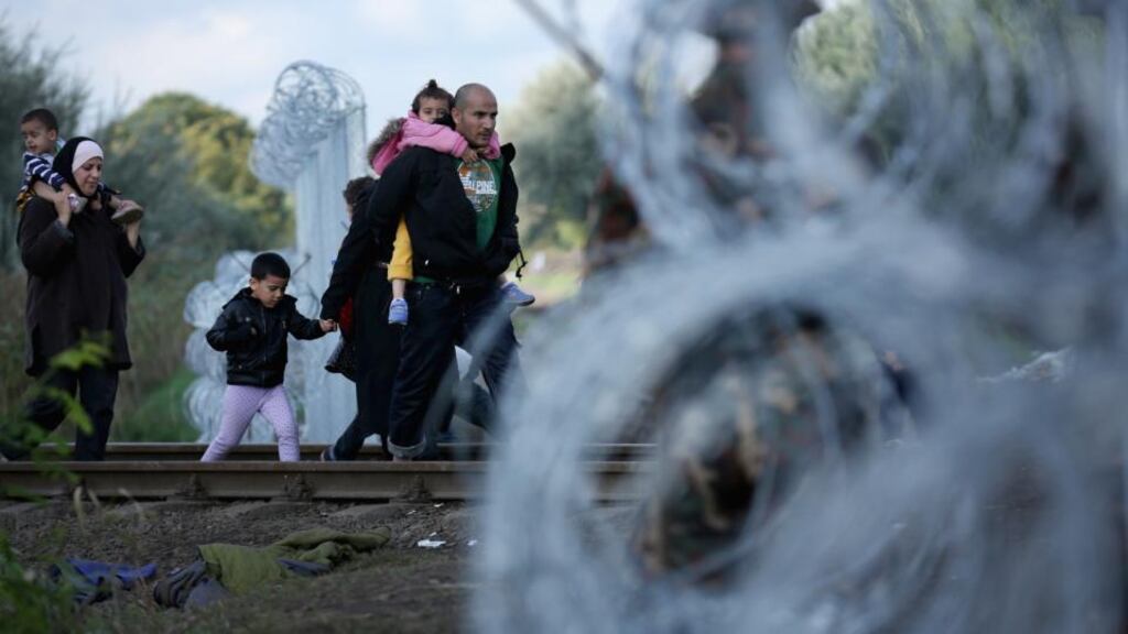 Migrants walk through a gap in the fence at Hungary’s border with Serbia, near Roszke. Photograph: Christopher Furlong/Getty