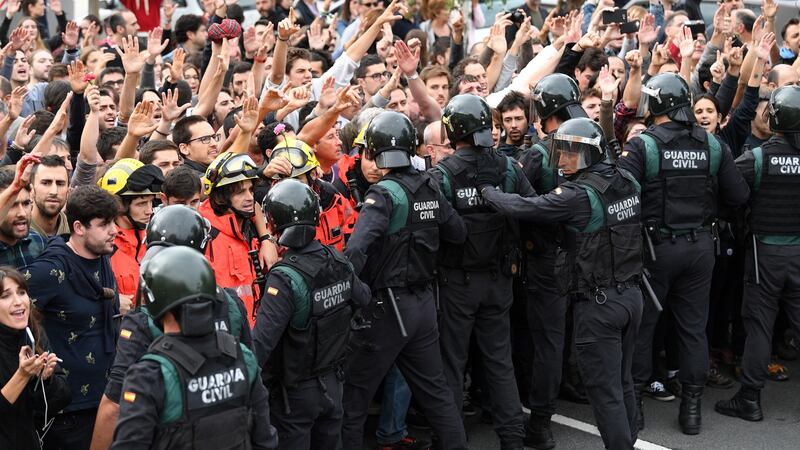 Catalan firefighters protect the crowds who raise their arms up as police move in during protests on the day of the unofficial independence referendum in Girona. Photograph: David Ramos/Getty Images