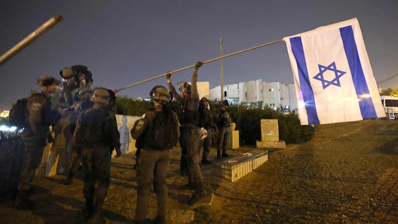 Israeli border police put back an Israeli flag after it was taken down by Palestinian protesters in east Jerusalem’s Sheikh Jarrah neighbourhood on Sunday. Photograph: Emmanuel Dunand/AFP via Getty Images