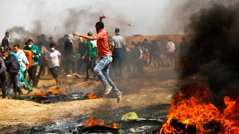A Palestinian demonstrator uses a slingshot to throw stones during clashes with Israeli security forces following a protest on the Israel-Gaza border. Photograph: Abed Mohammed/AFP/Getty Images.