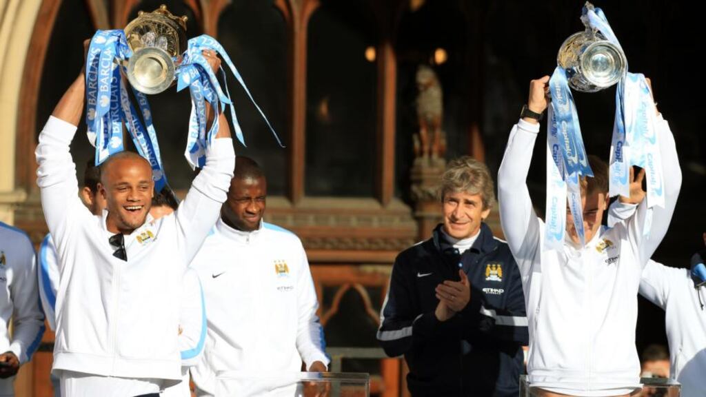Manchester City manager Manuel Pellegrini applauds as Joe Hart and Vincent Kompany lift the Premier League and Capital One Cup Trophies during the victory parade in Manchester yesterday. Photograph: Peter Byrne/PA Wire