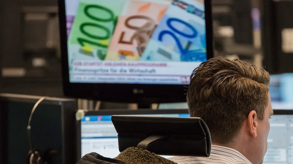 A financial trader monitors data on computer screens as a desktop television shows euro currency banknotes at the Frankfurt Stock Exchange in Frankfurt, Germany. German five-year yields turned positive for the first time since 2015 on calls for an end to the ECB’s bond-buying programme which is designed to support the euro zone economy. Photographer: Martin Leissl/Bloomberg
