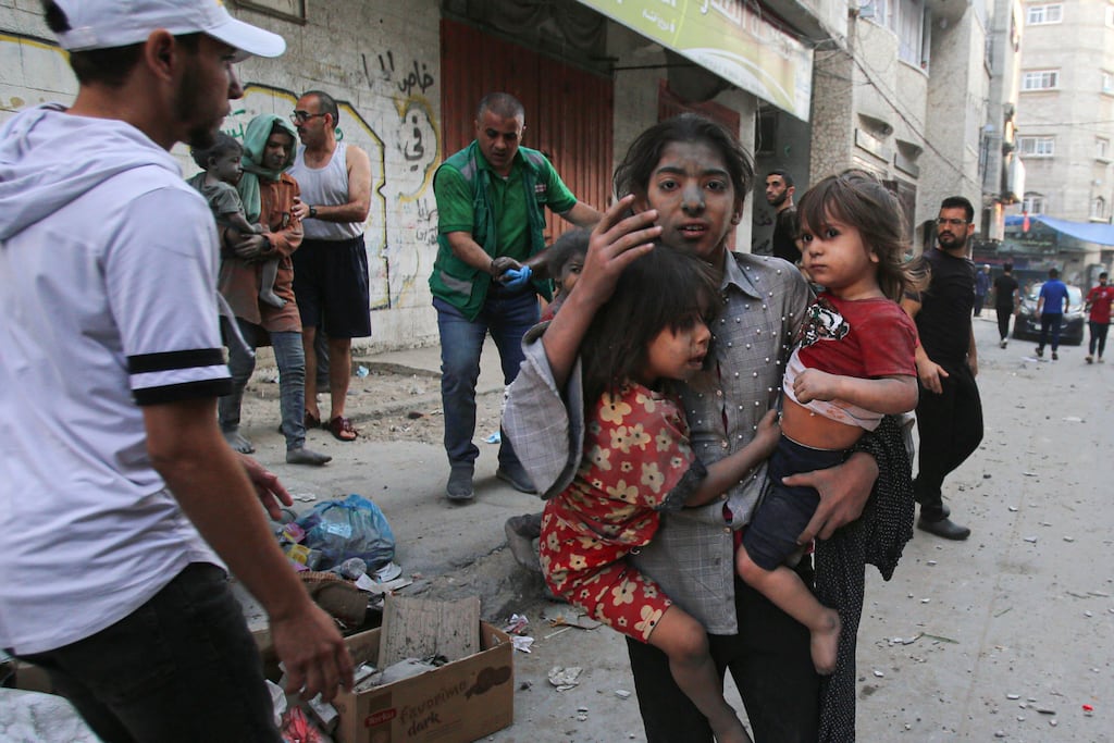 A Palestinian girl holds two children in Gaza City: There has been a glaring absence of reference to the humanity of Palestinians. Photograph: Bashar Taleb/AFP via Getty Images