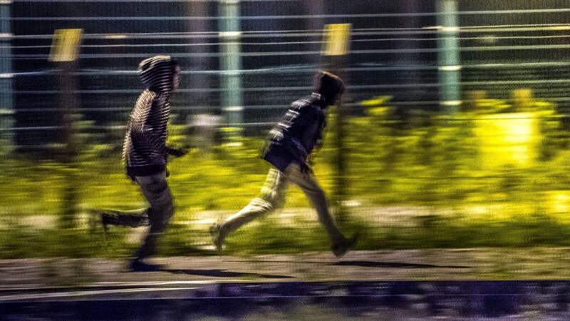 Migrants that have passed a first fence look for another passage to access the Eurotunnel terminal near Calais, northern France. Photograph: Philippe Huguen/AFP/Getty Images