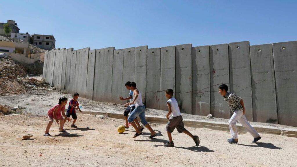 Palestinian children play near a section of the controversial Israeli barrier in Shuafat refugee camp in the West Bank near Jerusalem. Photograph: Reuters/Ammar Awad