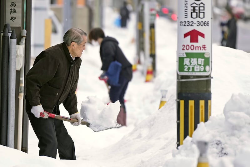 Residents shovel snow off a sidewalk in Kanazawa. Photograph: Kyodo News/AP
