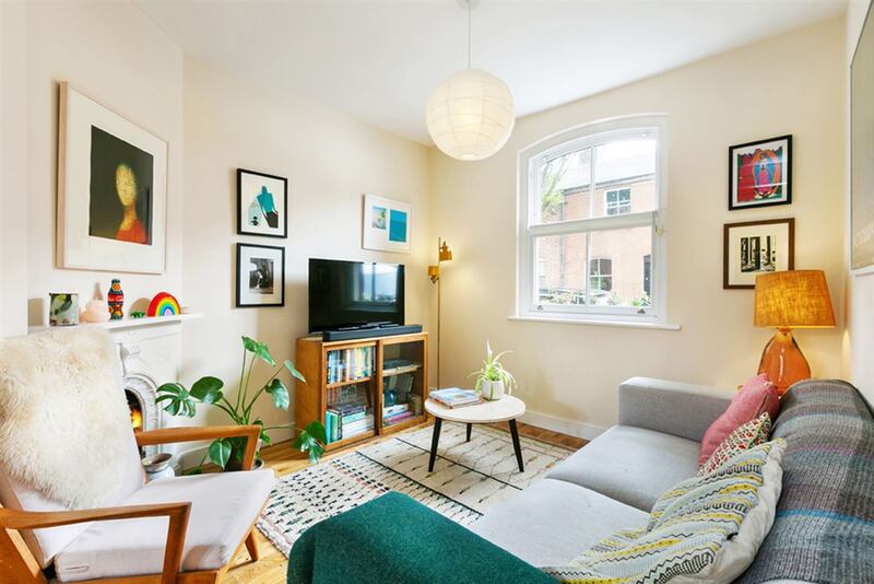 The living area is nestled to the front of the house, benefitting from the large sash window and decorative original fireplace, painted white.