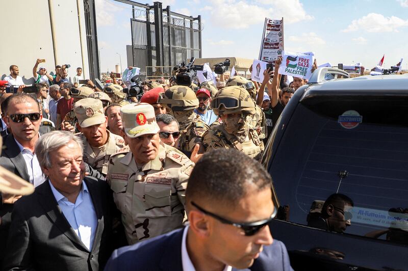 Protesters raise signs in solidarity with Palestinians in the Gaza Strip as Egyptian army officers and bodyguards escort UN secretary-general Antonio Guterres during his visit to oversee preparations for delivery of humanitarian aid to the Palestinian enclave, on the Egyptian side of the Rafah border, on Friday. Photograph: Kerolos Salah/AFP/Getty