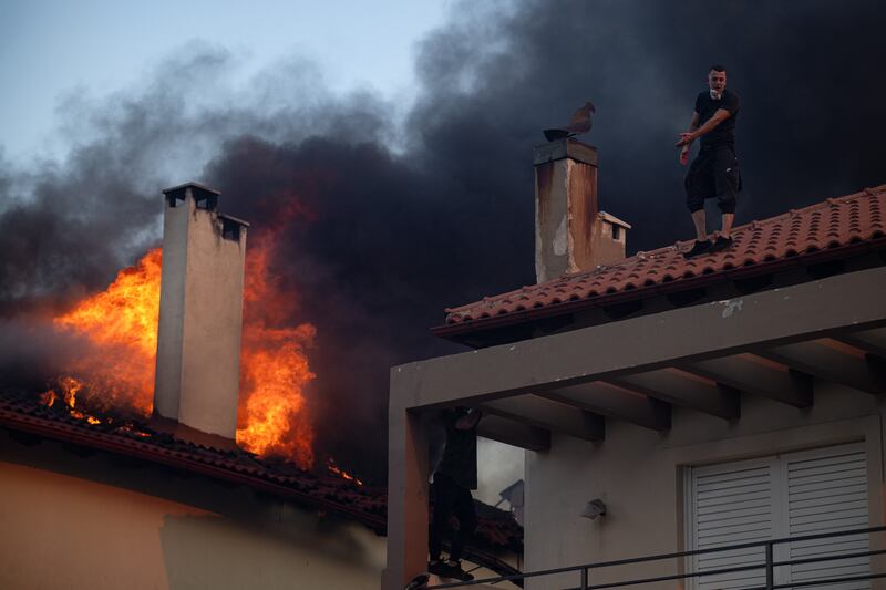 Residents try to extinguish the fire of a burning house during a wildfire in Kryoneri, near Athens. Photograph: Angelos Tzortzinis/Getty Images