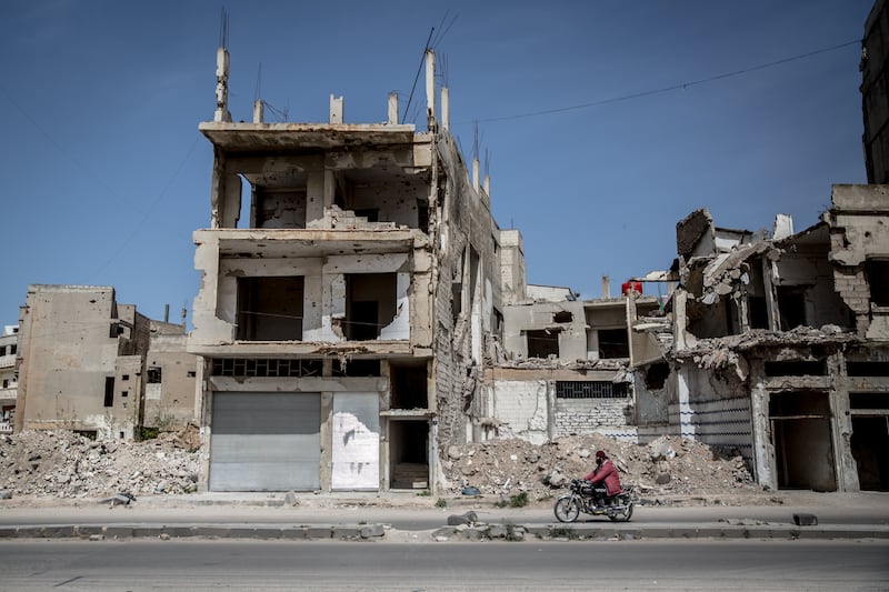 A man drives past a destroyed building in Homs. Photograph: Sally Hayden