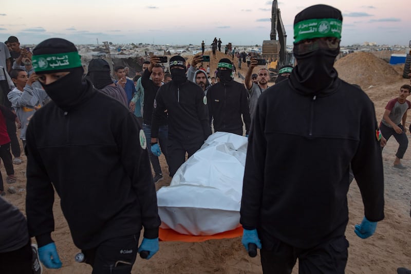 Hamas militants carry a white bag containing a body after retrieving it from a tunnel in Khan Yunis, southern Gaza, on Tuesday. Photograph: Haitham Imad/EPA