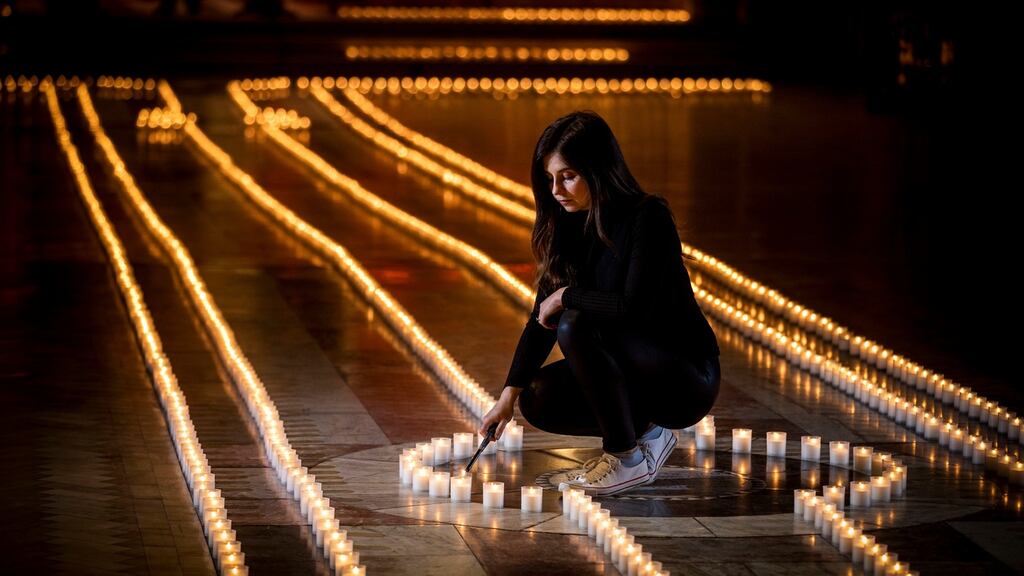 Holly Wilson, whose grandmother Ada Wilson died during the Covid-19 pandemic, is pictured lighting a candle in Belfast Cathedral earlier this week before a remembrance service for those who have died during the pandemic in Northern Ireland. Photograph: Liam McBurney/PA Wire.