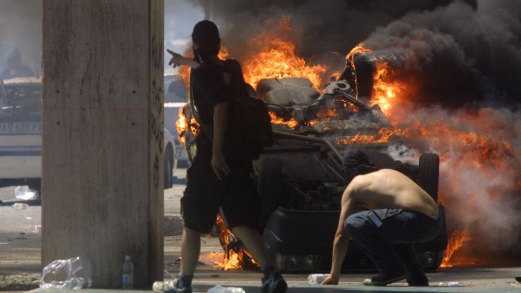 Anti-G8 protesters hide behind a burning car as they fight police on July 21st, 2001, in Genoa, Italy. Photograph: Sean Gallup/Getty Images