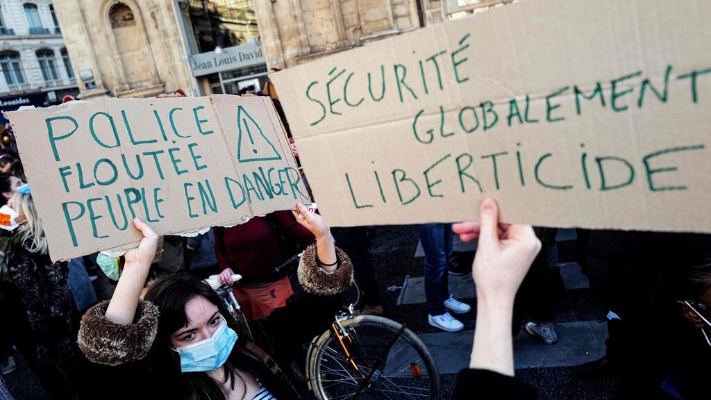 People hold placards reading “blurred police = people in danger” (left) and “overall freedom, killing security” in a protest against article 24 in Lyon. Photograph: Olivier Chassignole/AFP via Getty Images