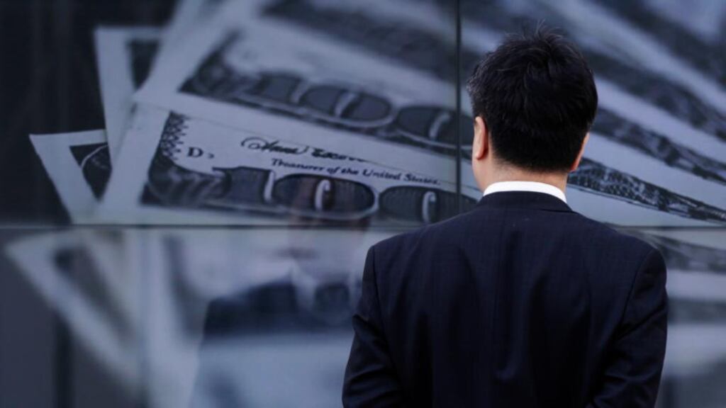 A businessman looks at a screen displaying a photo of US dollar bank notes in Tokyo today. The yen has hit fresh lows against a host of major currencies, resuming its slide after the Bank of Japan lost no time in launching its new easing policy to underline its determination to beat deflation. Photograph:  Toru Hanai/Reuters