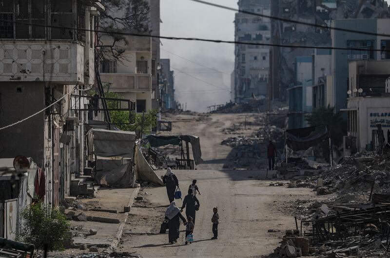 Palestinians walk as smoke rises following an Israeli air strike in the Tal Al Hawa neighbourhood of Gaza City on Friday. Photograph: Mohammed Saber/EPA