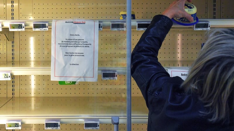 A sign reads “Due to a shortage of the raw material to make butter, we are not able to supply and sell you this product” as a woman takes a last pack of butter from an empty supermarket fridge on October 25th in Reze, western France. Photograph: Loic Venanceloic Venance/AFP/Getty Images