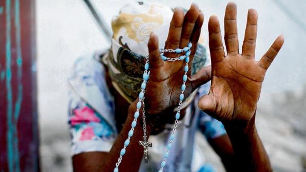 A woman prays during an open-air Mass celebrated outside Port-au-Prince's destroyed cathedral. Photograph: Jorge Silva/Reuters