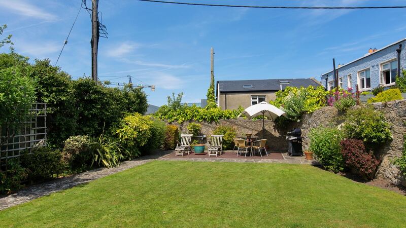The rear garden at Avoca Lodge is laid out as lawn bordered with shrubs and a patio to the rear