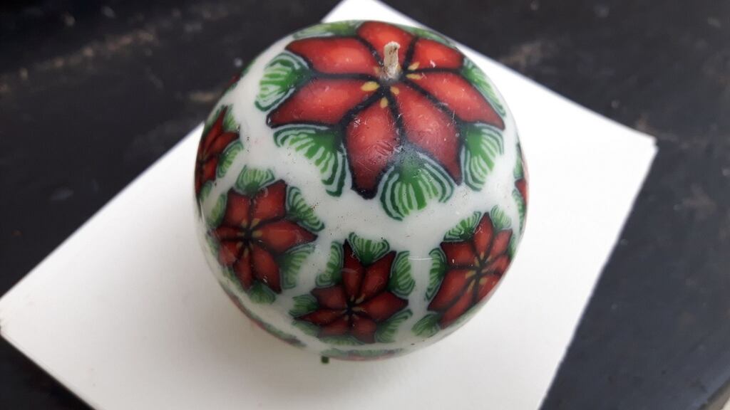 About the size of tennis ball, symmetrically designed with 20 poinsettias painted on its circumference and a wick that protruded stamen-like, from the top.