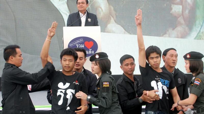 Two students were arrested by police officers and security guards as they flashed anti-coup sign in front of Prime Minister Prayut Chan-o-cha (back) while delivering a speech during his visit in Khon Kaen province, north eastern Thailand, yesterday. Photograph: EPA