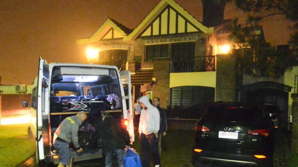 A man believed to be Uruguayan soccer player Luis Suarez (second from right) watches as bags are unloaded outside his home in the small coastal town of Solymar, near Montevideo on Friday. Photograph: Carlos Pazos/Reuters