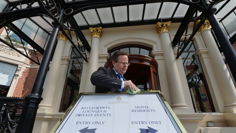 Shelbourne Hotel manager Lucius Farrell adjusting Covid-19 signage outside the hotel. Photograph: Alan Betson