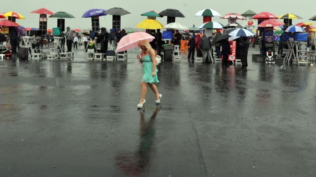 A racegoer uses an umbrella as rain falls during day four of the 2013 Galway Summer Festival at Galway Racecourse in  Ballybrit. Photograph: Barry Cronin/PA Wire