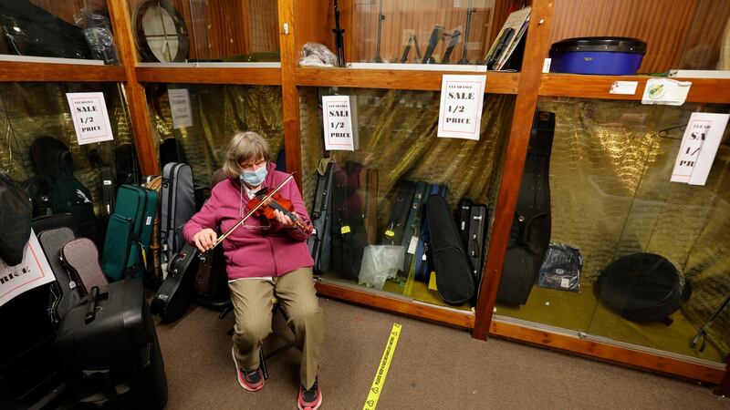 Maria Byrne plays a violin while waiting for one of her last customers. Photograph: Alan Betson/The Irish Times