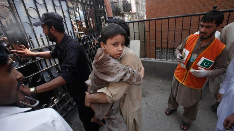 A man carries his injured son to hospital in Peshawar following today’s bombing. Photograph: Fayaz Aziz/Reuters