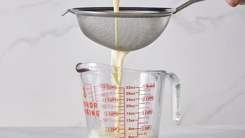 A heated cream is poured into a lemony mixture as preparation for lemon-labneh possets.
